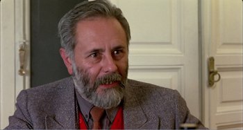 Movie still from “What Have I Done to Deserve This?” (1984), directed by Pedro Almodóvar – An older man with a gray beard is looking at the camera; Close Up shot, Over the shoulder angle