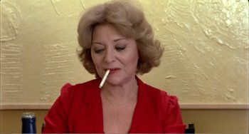 Movie still from “What Have I Done to Deserve This?” (1984), directed by Pedro Almodóvar – A woman in a red shirt is smoking a cigarette; Close Up shot, Low angle