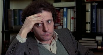 Movie still from “What Have I Done to Deserve This?” (1984), directed by Pedro Almodóvar – A man in a jacket and a tie is holding his hand up to his head; Close Up shot, High angle