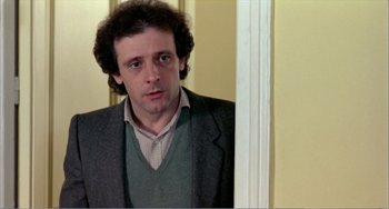 Movie still from “What Have I Done to Deserve This?” (1984), directed by Pedro Almodóvar – A man standing in front of a door looking to his left; Close Up shot, Low angle