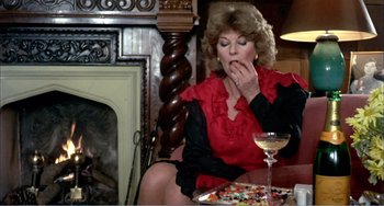 Movie still from “What Have I Done to Deserve This?” (1984), directed by Pedro Almodóvar – A woman sitting in front of a table with a glass of wine; Medium shot, Overhead angle