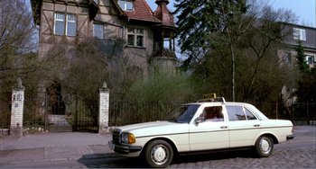 Movie still from “What Have I Done to Deserve This?” (1984), directed by Pedro Almodóvar – A white car parked on the side of the road; Wide shot, Low angle