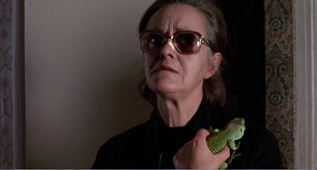 Movie still from “What Have I Done to Deserve This?” (1984), directed by Pedro Almodóvar – A woman holding a lizard in her hand; Close Up shot, Low angle