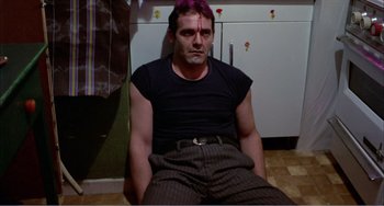 Movie still from “What Have I Done to Deserve This?” (1984), directed by Pedro Almodóvar – A man sitting on the floor in front of a refrigerator; Medium shot, High angle