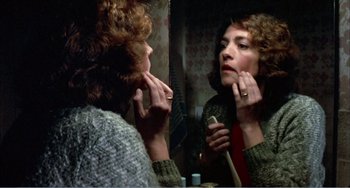 Movie still from “What Have I Done to Deserve This?” (1984), directed by Pedro Almodóvar – A woman looking in the mirror while putting lipstick on her lips; Close Up shot, Over the shoulder angle