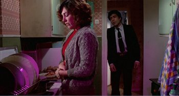 Movie still from “What Have I Done to Deserve This?” (1984), directed by Pedro Almodóvar – A man and a woman standing in a kitchen; Medium shot, High angle