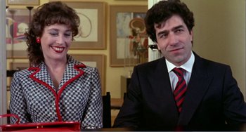Movie still from “What Have I Done to Deserve This?” (1984), directed by Pedro Almodóvar – A man and a woman sitting at a table in a room; Medium shot, Over the shoulder angle