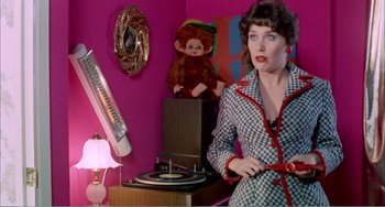 Movie still from “What Have I Done to Deserve This?” (1984), directed by Pedro Almodóvar – A woman standing in front of a pink wall; Medium shot, Over the shoulder angle
