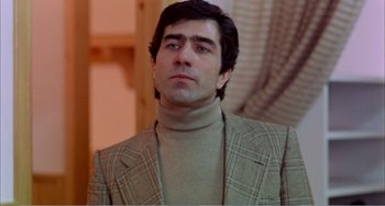 Movie still from “What Have I Done to Deserve This?” (1984), directed by Pedro Almodóvar – A person wearing a suit and tie; Close Up shot, Low angle