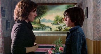 Movie still from “What Have I Done to Deserve This?” (1984), directed by Pedro Almodóvar – A woman talking to a young boy in front of a painting; Medium shot, Over the shoulder angle