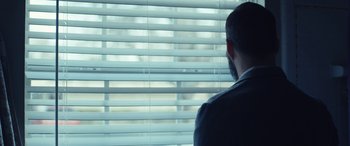 Movie still from “What Josiah Saw” (2021), directed by Vincent Grashaw – A man looking out of a window through blinds; Close Up shot, Low angle