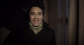 Movie still from “What We Do in the Shadows” (2014), directed by Taika Waititi – A man wearing a black coat and a neck scarf; Close Up shot, Over the shoulder angle