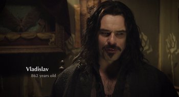 Movie still from “What We Do in the Shadows” (2014), directed by Taika Waititi – A person with long black hair; Close Up shot, Over the shoulder angle