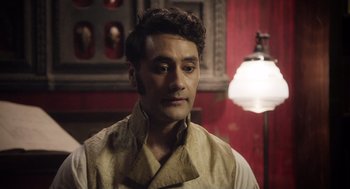 Movie still from “What We Do in the Shadows” (2014), directed by Taika Waititi – A person wearing a shirt and tie; Close Up shot, Over the shoulder angle