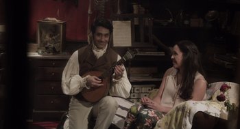 Movie still from “What We Do in the Shadows” (2014), directed by Taika Waititi – A man and a woman sitting on a chair playing a guitar; Medium shot, Over the shoulder angle