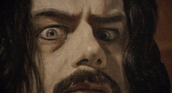 Movie still from “What We Do in the Shadows” (2014), directed by Taika Waititi – A painting of a man's face; Extreme Close Up shot, Overhead angle