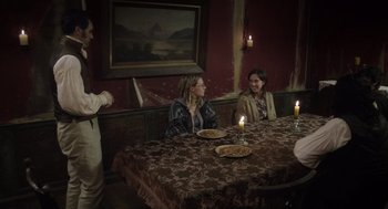 Movie still from “What We Do in the Shadows” (2014), directed by Taika Waititi – A group of people sitting at a table with plates of food on it; Wide shot, High angle