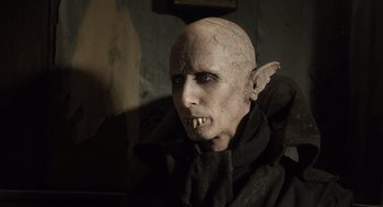 Movie still from “What We Do in the Shadows” (2014), directed by Taika Waititi – A person wearing a costume; Close Up shot, Over the shoulder angle