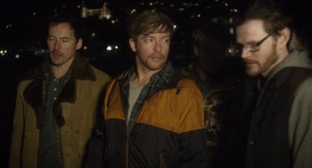 Movie still from “What We Do in the Shadows” (2014), directed by Taika Waititi – A person wearing a jacket; Medium shot, Over the shoulder angle