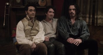 Movie still from “What We Do in the Shadows” (2014), directed by Taika Waititi – A group of men sitting next to each other on top of a couch; Medium shot, High angle