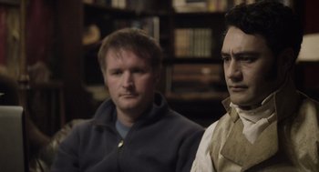 Movie still from “What We Do in the Shadows” (2014), directed by Taika Waititi – Two men sitting next to each other in front of a book shelf; Close Up shot, Over the shoulder angle