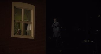 Movie still from “What We Do in the Shadows” (2014), directed by Taika Waititi – A woman standing in front of a window at night; Wide shot, Low angle