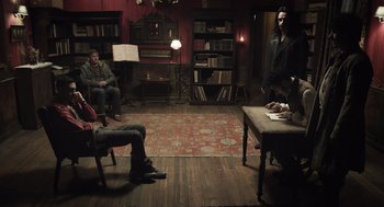 Movie still from “What We Do in the Shadows” (2014), directed by Taika Waititi – A group of people sitting in a living room; Wide shot, High angle