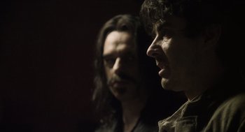 Movie still from “What We Do in the Shadows” (2014), directed by Taika Waititi – Two men standing next to each other in a dark room; Close Up shot, Over the shoulder angle