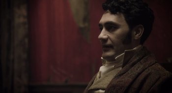 Movie still from “What We Do in the Shadows” (2014), directed by Taika Waititi – A person wearing a costume; Close Up shot, Over the shoulder angle