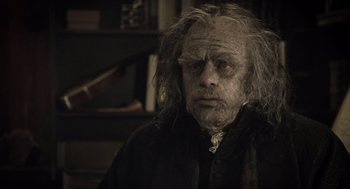 Movie still from “What We Do in the Shadows” (2014), directed by Taika Waititi – An old man with long white hair is looking at the camera; Close Up shot, Low angle