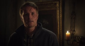 Movie still from “What We Do in the Shadows” (2014), directed by Taika Waititi – A man standing in front of a mirror in a dark room; Close Up shot, Over the shoulder angle