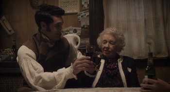 Movie still from “What We Do in the Shadows” (2014), directed by Taika Waititi – An older woman holding a wine glass while a young man looks on; Medium shot, Over the shoulder angle