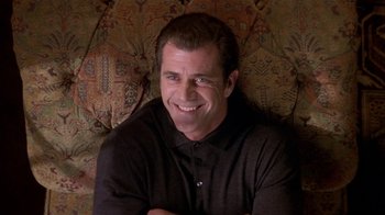 Movie still from “What Women Want” (2000), directed by Nancy Meyers – A man sitting on top of a couch smiling for the camera; Close Up shot, Over the shoulder angle