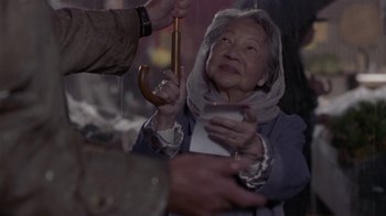 Movie still from “What Women Want” (2000), directed by Nancy Meyers – An older woman holding a wooden stick in front of a crowd; Close Up shot, Over the shoulder angle