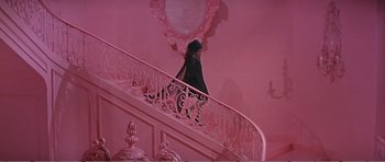 Movie still from “What a Way to Go!” (1964), directed by J. Lee Thompson – A woman walking down a staircase in a pink room; Wide shot, High angle