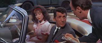 Movie still from “What a Way to Go!” (1964), directed by J. Lee Thompson – A man and a woman sitting next to each other in a car; Medium shot, Over the shoulder angle