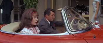 Movie still from “What a Way to Go!” (1964), directed by J. Lee Thompson – A man and a woman sitting in a red car; Medium shot, High angle
