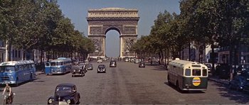 Movie still from “What a Way to Go!” (1964), directed by J. Lee Thompson – Cars driving down the street in front of the arc de triomphe in paris; Extreme Wide shot, High angle