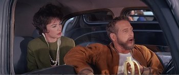 Movie still from “What a Way to Go!” (1964), directed by J. Lee Thompson – A man and a woman sitting in the back of a car; Close Up shot, Over the shoulder angle