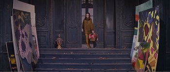 Movie still from “What a Way to Go!” (1964), directed by J. Lee Thompson – A woman is walking down the stairs with a bag; Wide shot, Low angle