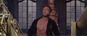 Movie still from “What a Way to Go!” (1964), directed by J. Lee Thompson – A man in a black shirt is looking up; Medium shot, Low angle