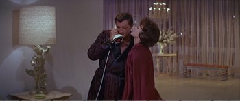 Movie still from “What a Way to Go!” (1964), directed by J. Lee Thompson – A man and a woman are kissing in front of a mirror; Medium shot, Low angle