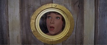 Movie still from “What a Way to Go!” (1964), directed by J. Lee Thompson – A woman's face in a porthole window; Close Up shot, Overhead angle