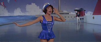 Movie still from “What a Way to Go!” (1964), directed by J. Lee Thompson – A woman wearing a blue bathing suit and a sailor hat; Medium shot, Low angle