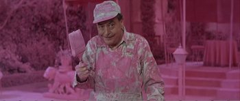 Movie still from “What a Way to Go!” (1964), directed by J. Lee Thompson – A man in a pink uniform holding a pink spatula; Medium shot, Over the shoulder angle