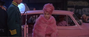 Movie still from “What a Way to Go!” (1964), directed by J. Lee Thompson – A woman in a pink fur coat in front of a pink car; Medium shot, High angle