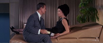 Movie still from “What a Way to Go!” (1964), directed by J. Lee Thompson – A man and a woman sitting on top of a wooden bench; Medium shot, Low angle