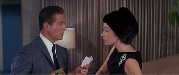 Movie still from “What a Way to Go!” (1964), directed by J. Lee Thompson – A man and a woman are holding papers in their hands; Close Up shot, Over the shoulder angle