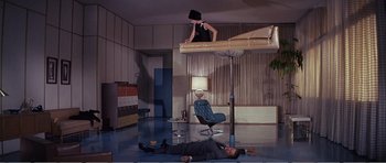 Movie still from “What a Way to Go!” (1964), directed by J. Lee Thompson – A man and a woman are laying on the floor in a living room; Wide shot, High angle