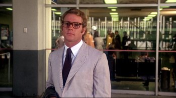 Movie still from “What's Up, Doc?” (1972), directed by Peter Bogdanovich – A man in a suit and tie standing in front of a building; Medium shot, Low angle